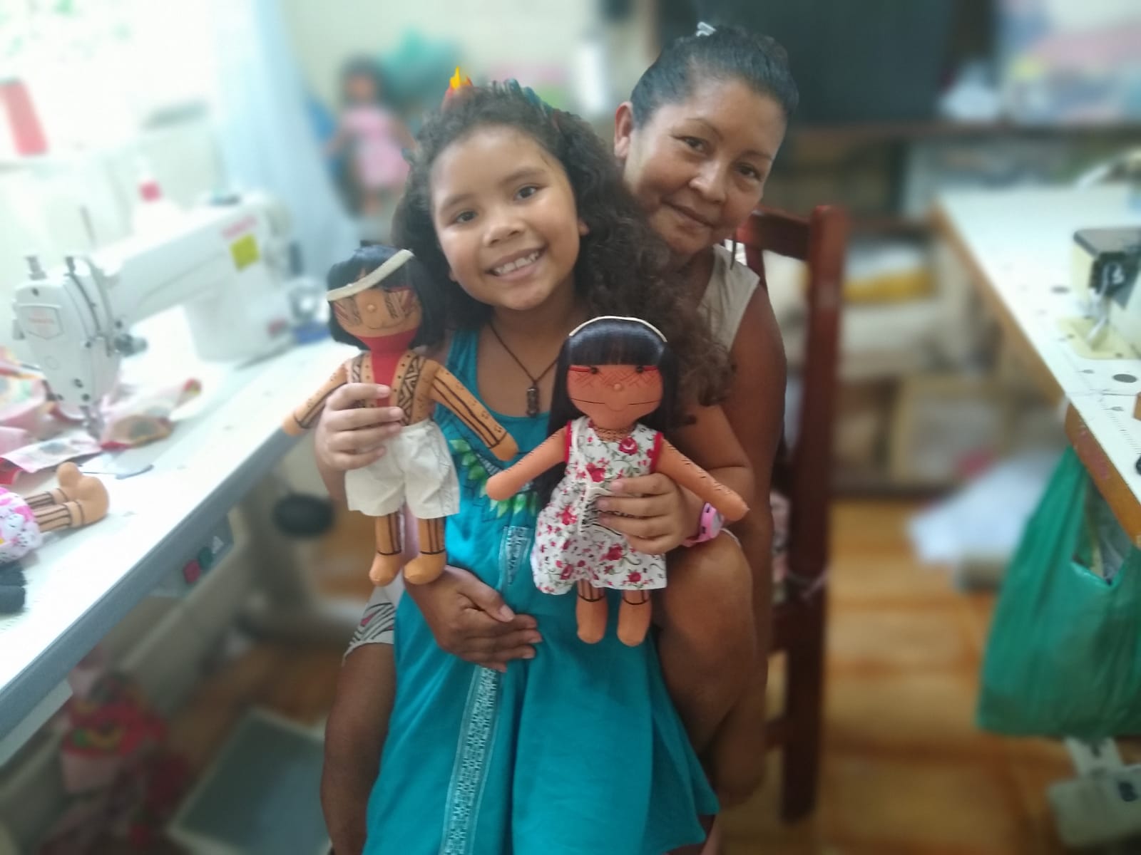 Luakam e Anaty, sua neta, apresentando um casal de bonecas Anambé. O menino é o Guerreiro Mayauê Anambé e a menina é a Anaty Anambé. Esta foto foi postada nas redes sociais da marca para divulgação. Para Luakam a base da relação entre ela e sua neta é o amor.