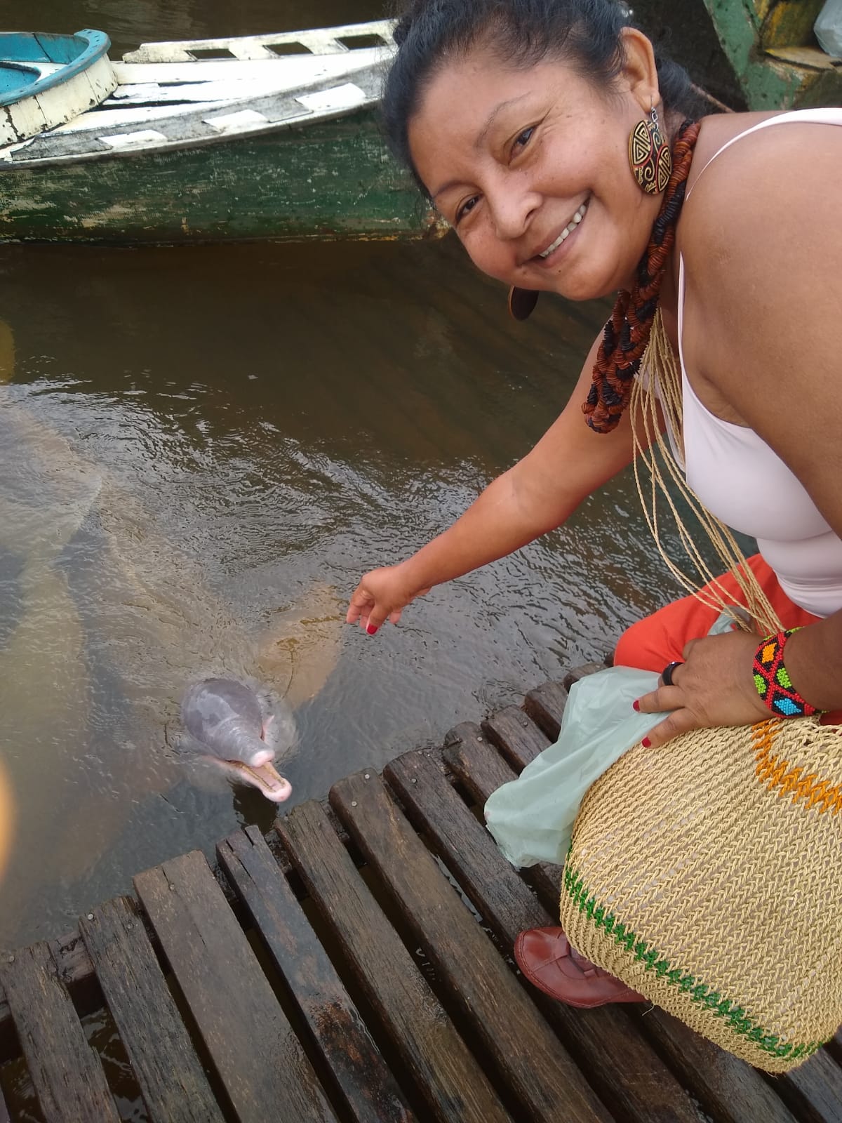 Esta foto foi tirada durante uma viagem que Luakam fez para a aldeia Anambé. Antes de chegar no destino final parou em Mocajuba, um braço do Rio Amazonas, para tomar um Tacacá e ao chegar na margem do rio de Mocajuba ela foi agraciada pela recepção de vários botos-cor-de-rosa do Rio Amazonas. Este foi o seu primeiro contato com botos. 
Esta foto foi tirada durante uma viagem que Luakam fez para a aldeia Anambé. Antes de chegar no destino final parou numa cidade para tomar um Tacacá e ao chegar na margem do rio de Mocajuba ela foi agraciada pela recepção de vários botos-cor-de-rosa do Rio Amazonas. Este foi o seu primeiro contato com botos. 
Há uma lenda no Pará de que o boto é encantado, então esse dia foi muito emocionante para Luakam. Ela também ficou impressionada com a inteligência dos botos. Um parente indígena entrou dentro d'água e fingiu que estava se afogando, então este boto veio rapidinho e entrou debaixo do braço dele e tentou levá-lo para a superfície.