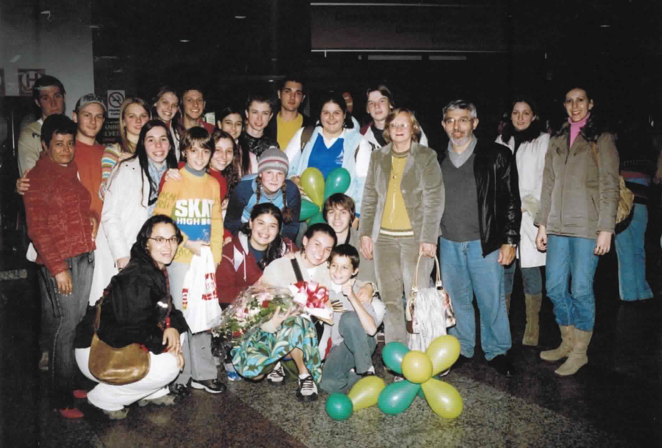 Bruna voltou do intercâmbio e foi recebida pela família e amigos no aeroporto. Sua mãe organizou um ônibus para transportar todos. Embaixo, está Bruna agachada, abraçada com o primo Lucas