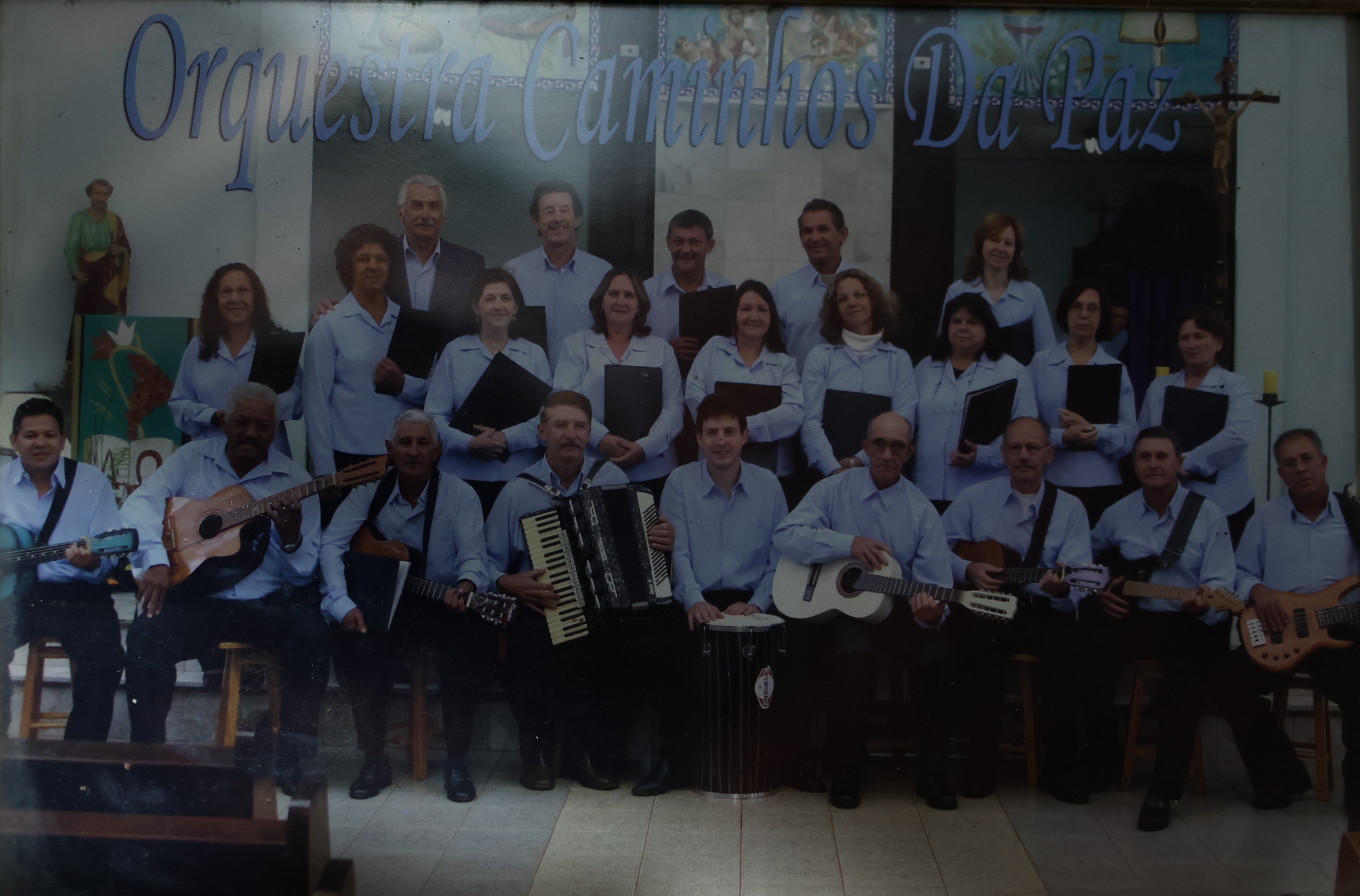 Nesta foto, Seu Jorge está junto de sua esposa e de casais de amigos na Orquestra Caminho da Paz. Trata-se de uma orquestra sertaneja.