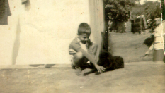 José Antonio e seu cachorro, Pelé, em frente à casa de sua tia Lina, uma segunda mãe. No lado direito da fotografia, Corina, sua mãe.