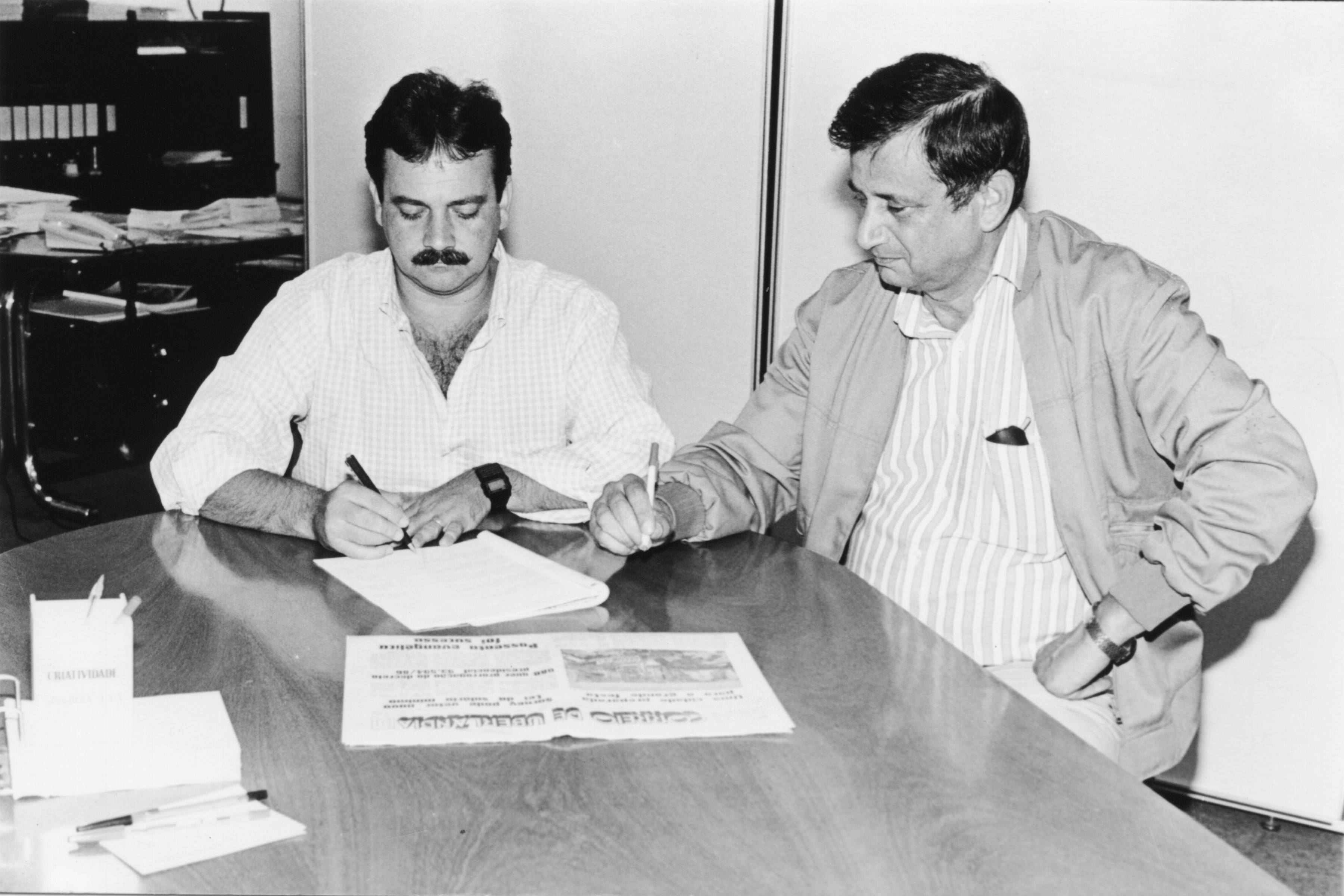 Arly e Dílson Dalpiaz assinando um contrato de publicidade.