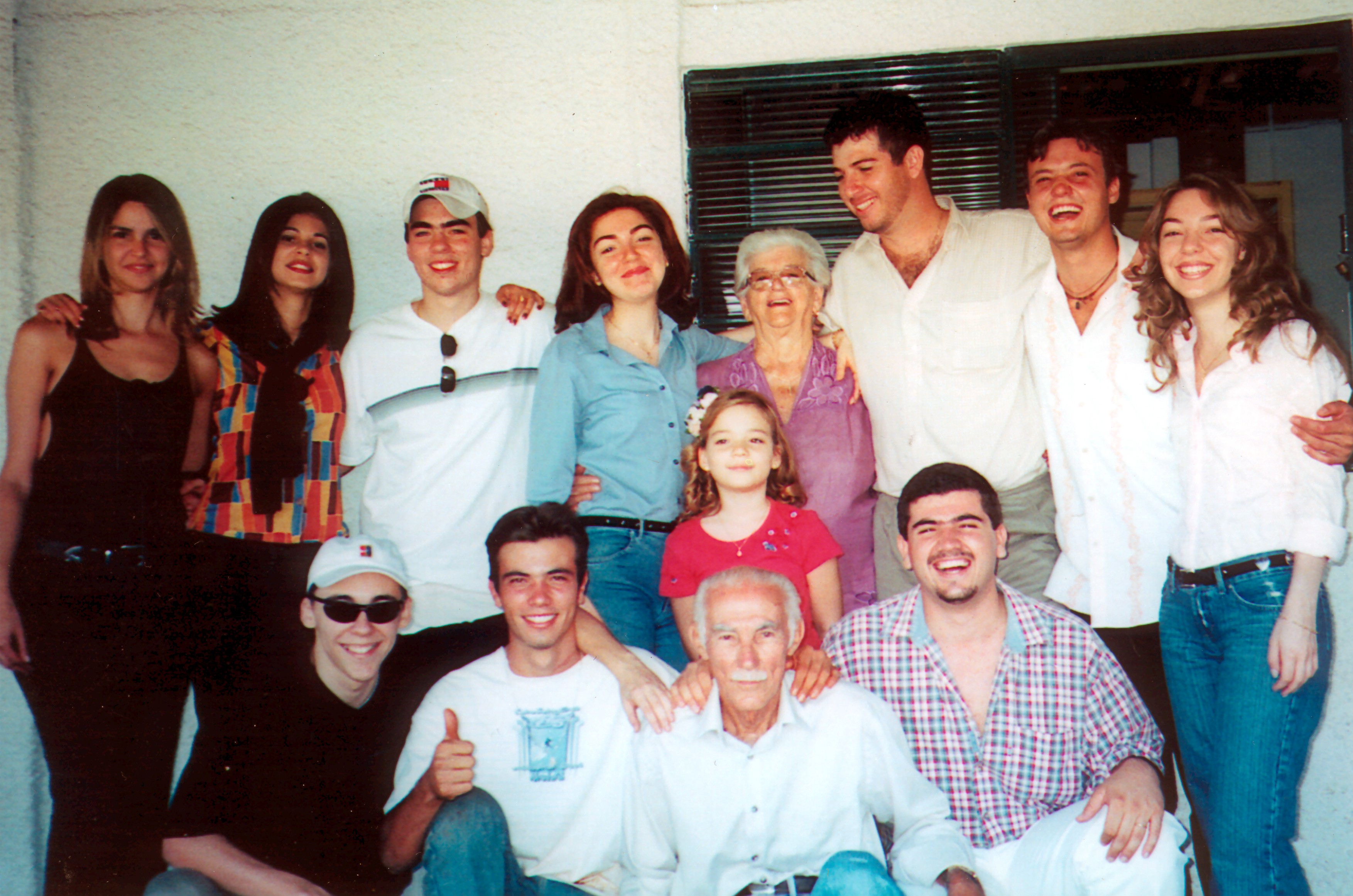 Alderico (agachado, terceira pessoa) e sua esposa Ana (em pé, quinta pessoa) 5a esq dir no alto) em sua residência, junto aos netos. Os netos estão na residência de Alderico.