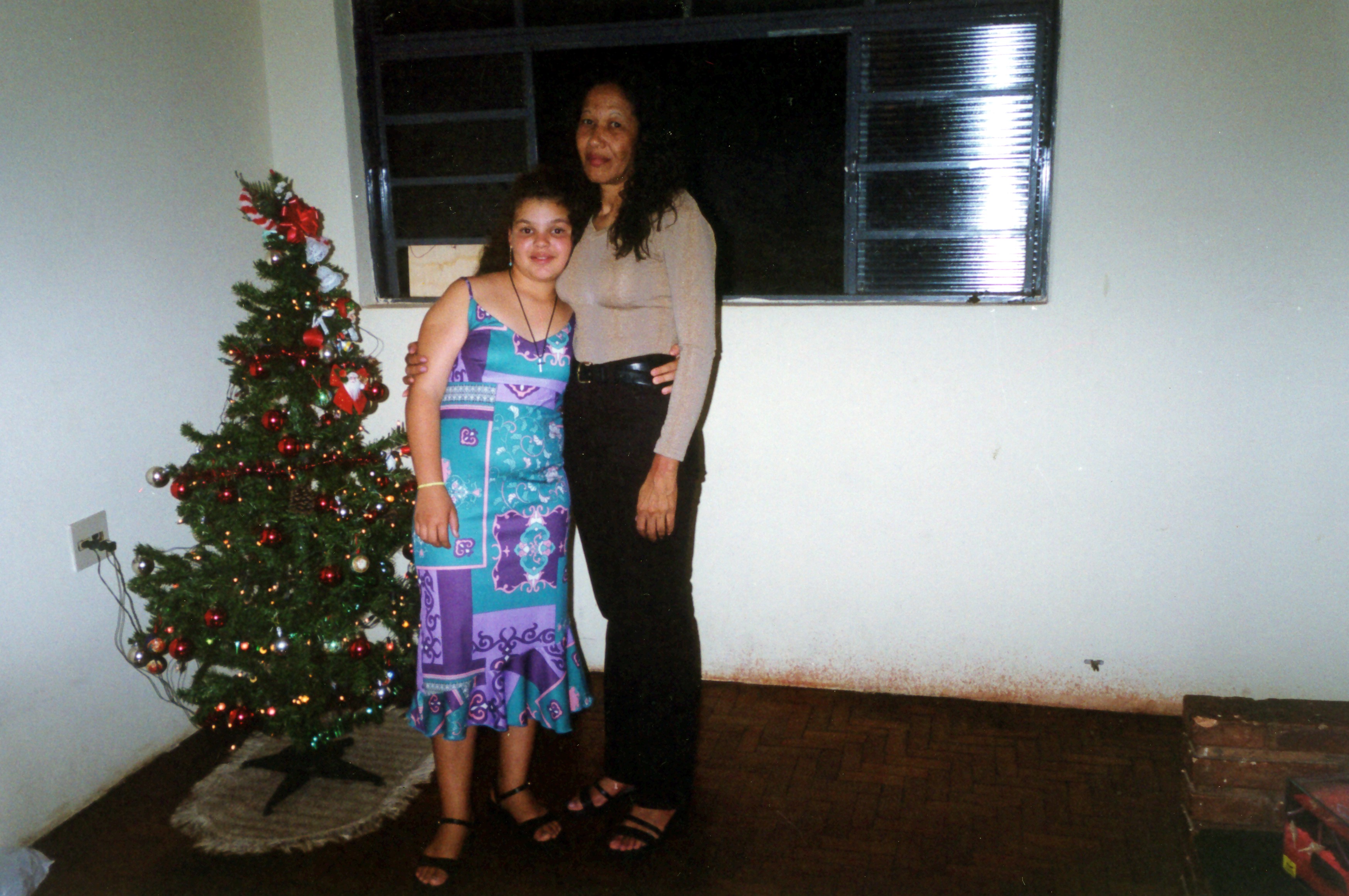 Maria Amélia e a filha Aline Cristina abraçadas ao lado da árvore de Natal.