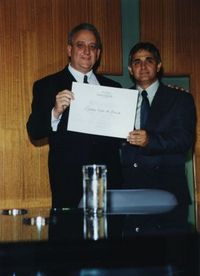 Evauri (à esquerda) recebendo o certificado de Honra ao Mérito de cidadão uberlandense das mãos do vereador Vilmar Resende (à direita).