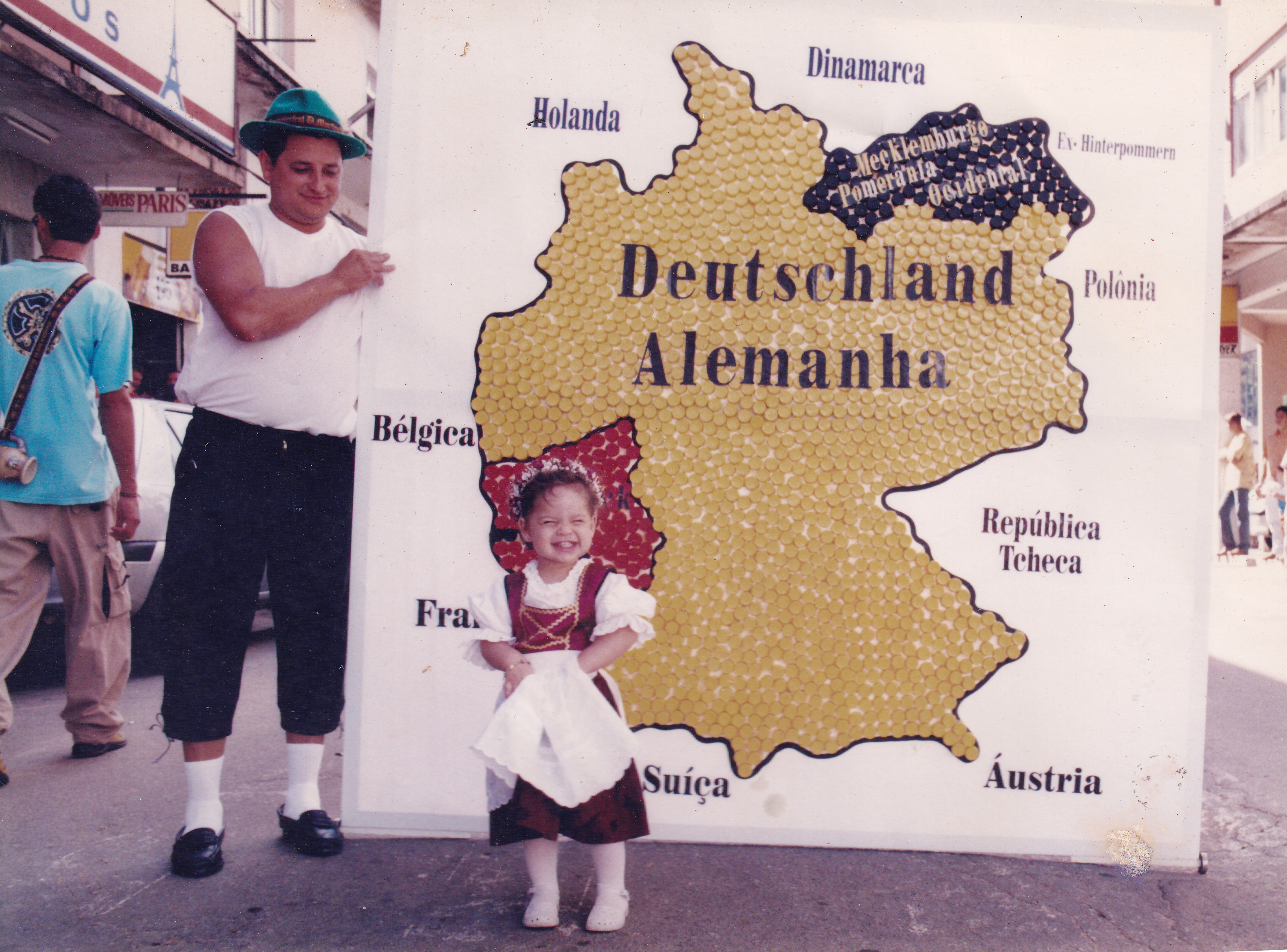 Nínive, criança, no Sommerfest, com seu pai (Rogério de Carvalho). 
Seu pai trabalhava na prefeitura e, para esta celebração, fez o mapa da Alemanha com tampinha de garrafa pet. A foto foi tirada na Avenida Presidente Vargas.