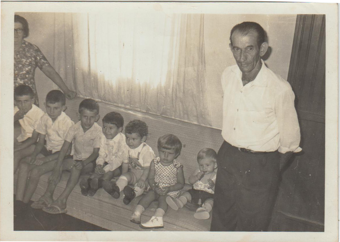 Foto tirada na casa dos avós em reunião de família no almoço de natal. Na foto estão todos os netos em linha cronológica junto com os avós. Na foto estão a avó Maria, o irmão Carlos, o irmão Luiz, o irmão Marcos, o primo João, o primo Márcio, a depoente Maria Luzia, o primo Sérgio e o avô Angelo.