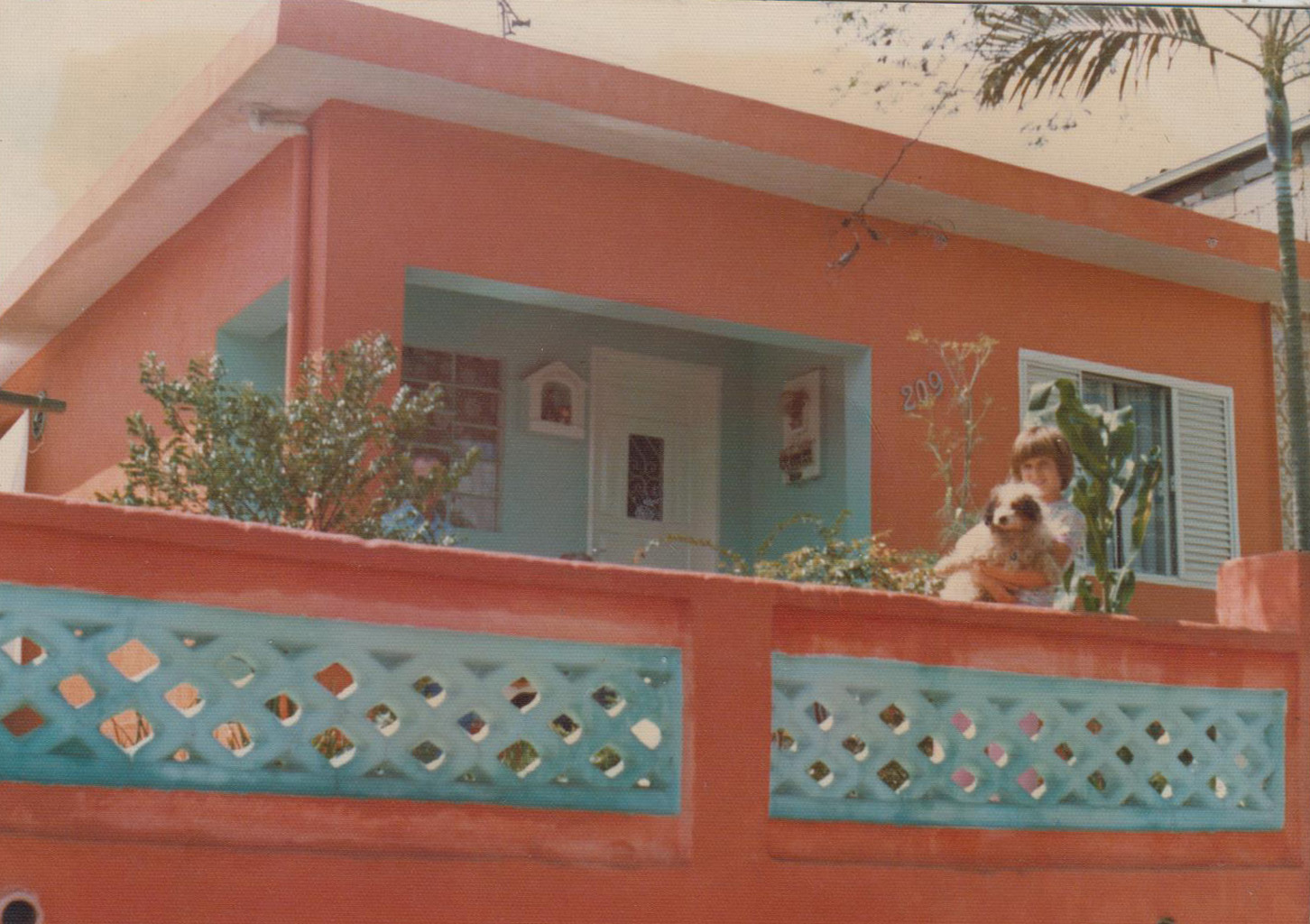 Foto de Maria Luzia na casa que é até hoje dos seus pais e foi a casa onde a depoente cresceu. Na foto está com o seu cachorro Piqui, que veio do Sítio onde moraram em Presidente Bernardes.