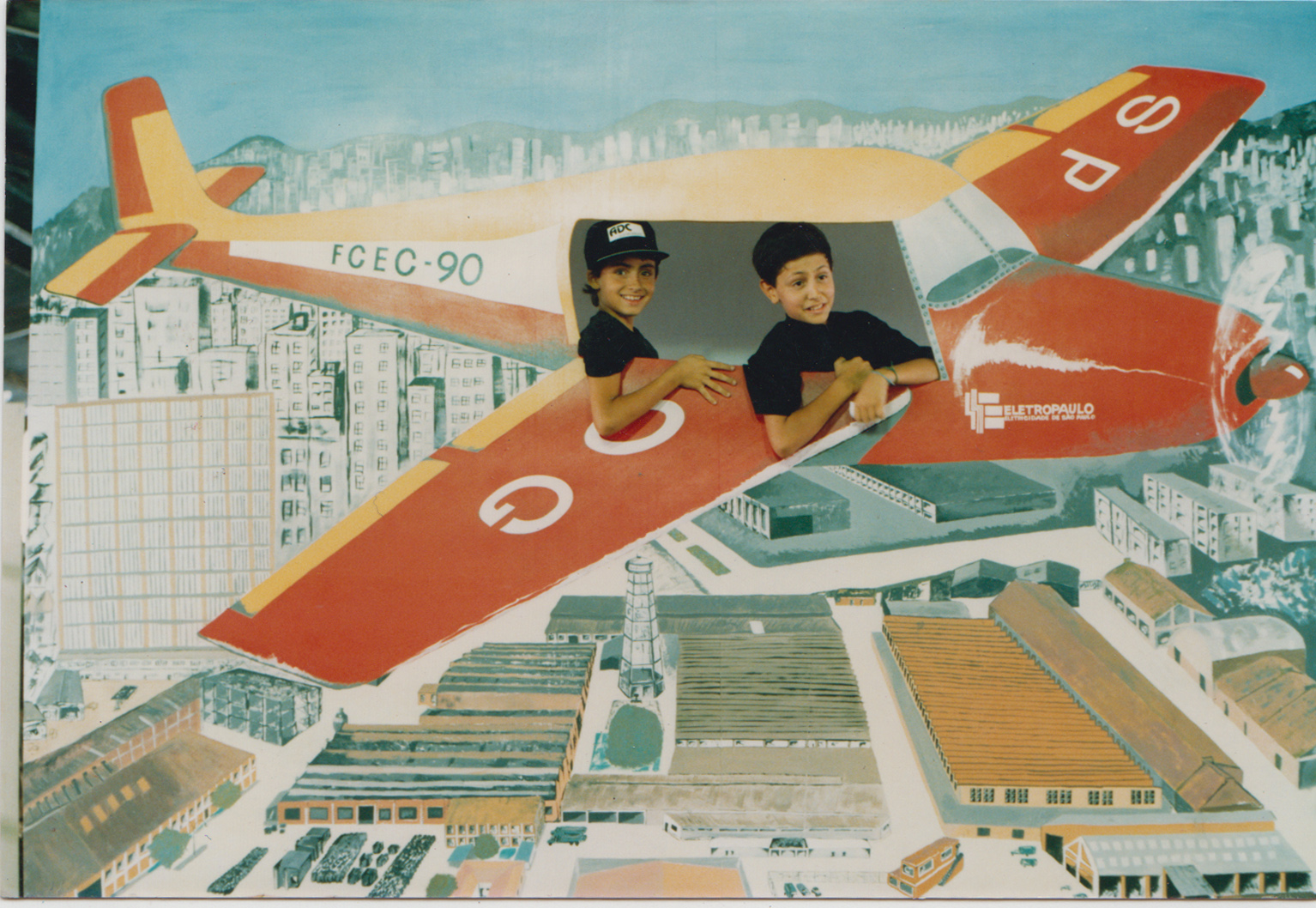 Thiago (à esquerda), o filho de Cláudio, posa para foto em um painel com desenho de avião durante a confraternização de final de ano dos funcionários da Eletropaulo.