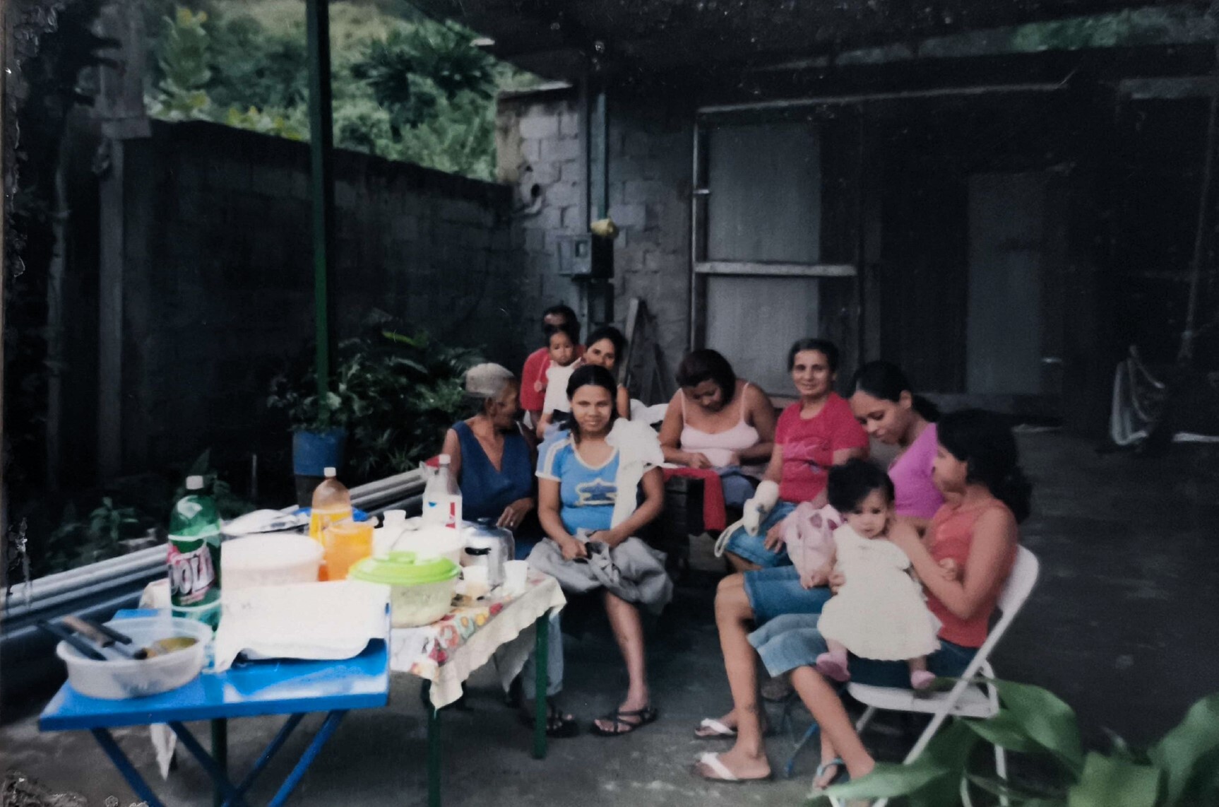 A fotografia registra uma das muitas festas realizadas no espaço que, anos mais tarde, se transformaria na sede da ONG De Bem com o Mangue. O ambiente retrata o período anterior à grande reforma de 2015, preservando a atmosfera comunitária e espontânea das celebrações locais. Ao fundo, destacam-se Adriana e sua filha mais velha, Marisol.