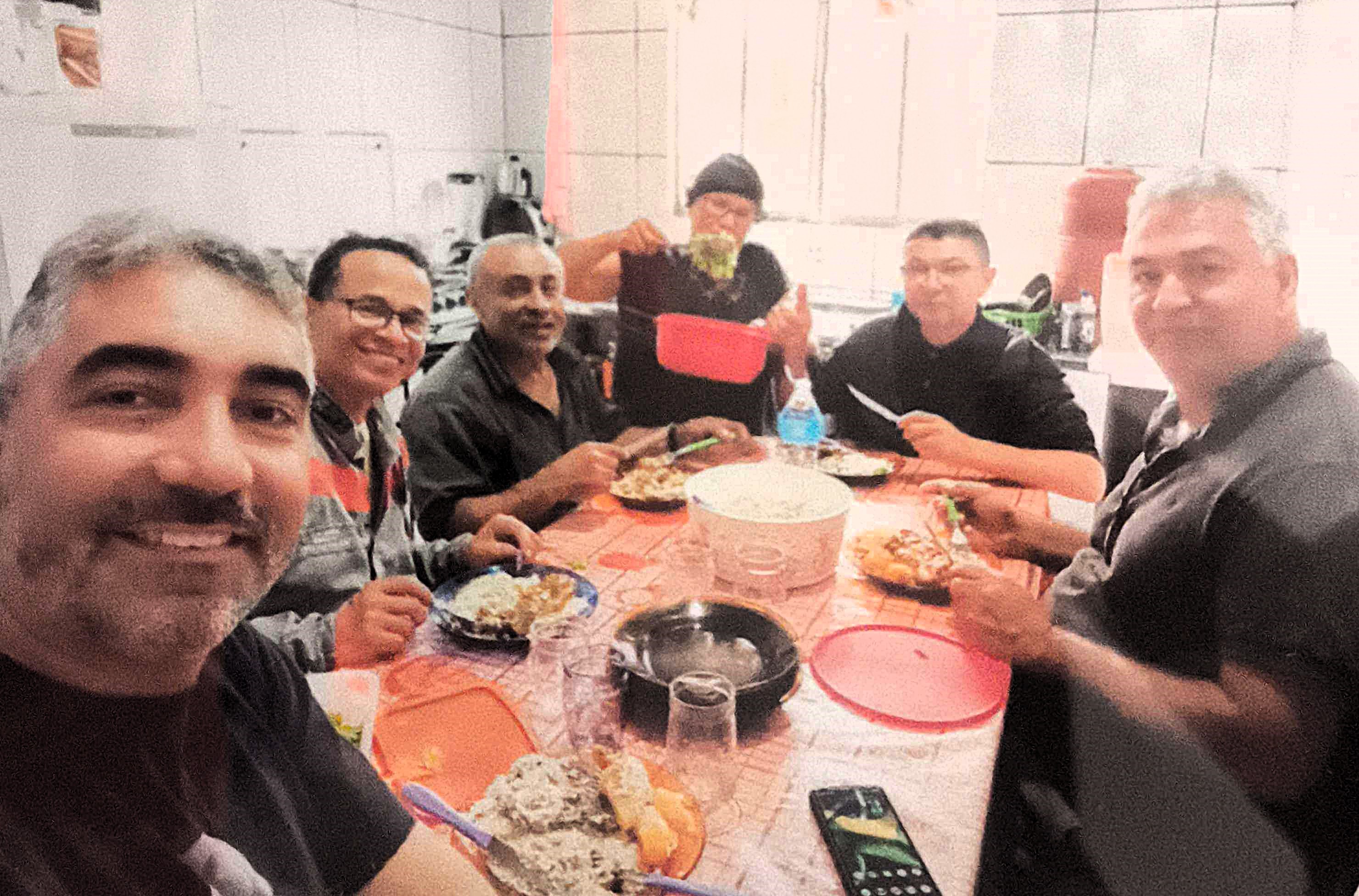 Em selfie, o engenheiro Giba, da obra da Igreja da Divina Misericórdia, na Vila Esperança, durante um dos almoços que reuniam os envolvidos na construção. Vemos Edite servindo a comida, função inicialmente designada pelo padre, mas que logo se transformou em responsabilidade integral dela, símbolo de sua dedicação.