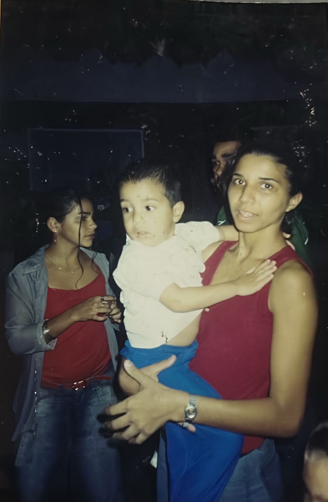 Comemoração do aniversário de 3 anos de Kadu, filho de Patrícia, realizada no bairro dos Pilões, em Cubatão. A imagem registra mãe e filho em um momento de celebração da infância. Ao fundo, aparece Tatinha, sobrinha de Patrícia, compondo um cenário familiar que evidencia a presença intergeracional e os vínculos afetivos construídos no cotidiano.