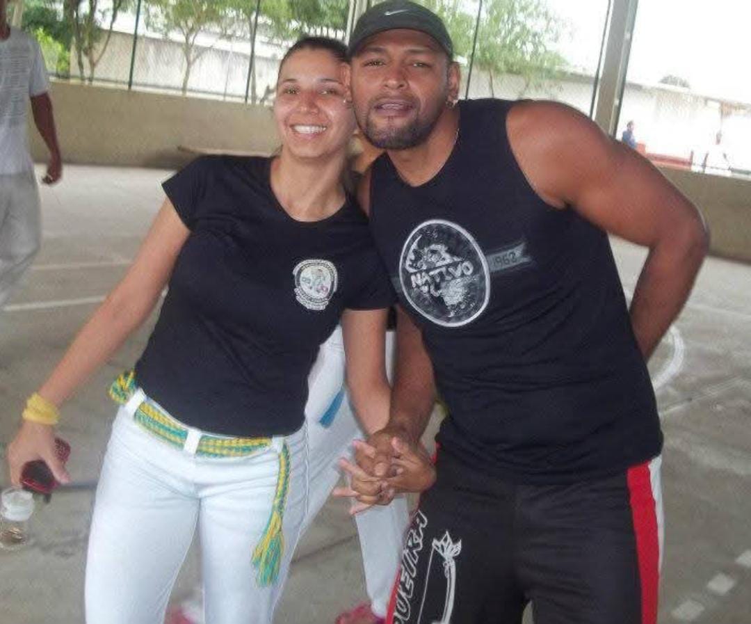 Patrícia aparece ao lado de seu esposo, Cláudio, em um registro realizado em Cubatão. Ambos praticam capoeira e se conheceram nesse ambiente, onde Cláudio também atua como contramestre de Patrícia. A fotografia registra o casal em um contexto ligado à prática que une suas trajetórias pessoais e formativas.