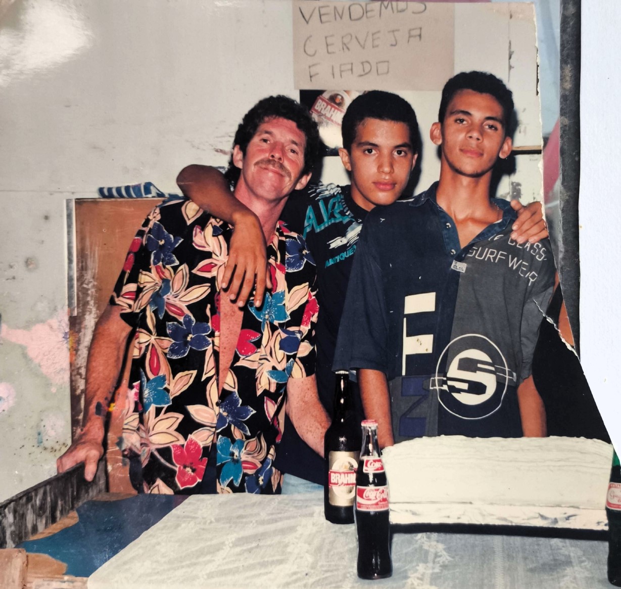 Nesta imagem, Tigrão, esposo de Dona Cícera, aparece ao lado dos filhos Patrique e Plínio durante uma comemoração de aniversário no Bar do Forró, espaço emblemático da Vila Esperança nos anos 1980 e 1990, conhecido por abrigar festas e forrós memoráveis. O registro destaca o laço entre pai e filhos, revelando um momento de afeto e união familiar em meio à efervescência cultural do bairro. A imagem também remete à atuação de Tigrão como figura ativa na vida comunitária e na construção de espaços de convivência.