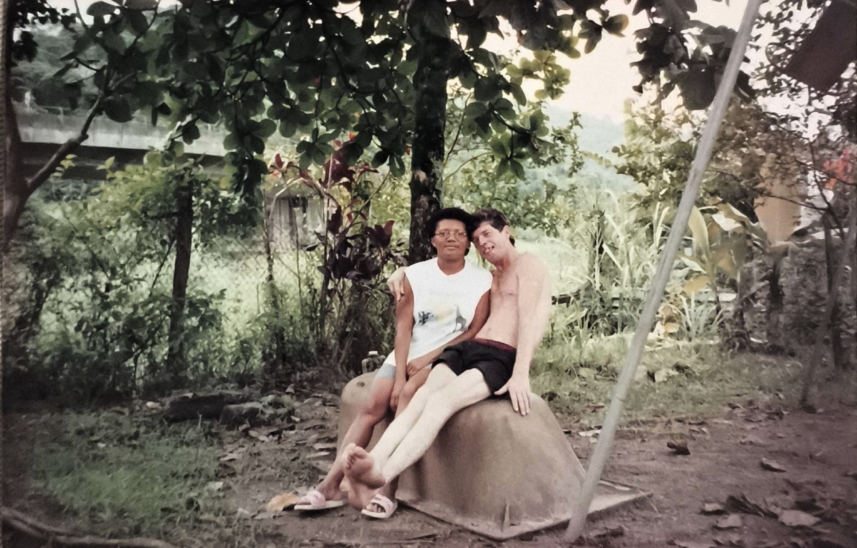 Nesta imagem, Dona Cícera aparece com seu marido, Tigrão, em um momento que remete à trajetória compartilhada na construção da vida familiar e comunitária na Vila Esperança. O quintal onde estão, anteriormente cercado por mata e vazio, viria a se transformar com o tempo: hoje abriga a casa de seu filho Patrique e outras moradias de aluguel que ela passou a administrar. O registro carrega a memória da ocupação do território e da presença ativa do casal na consolidação da comunidade.