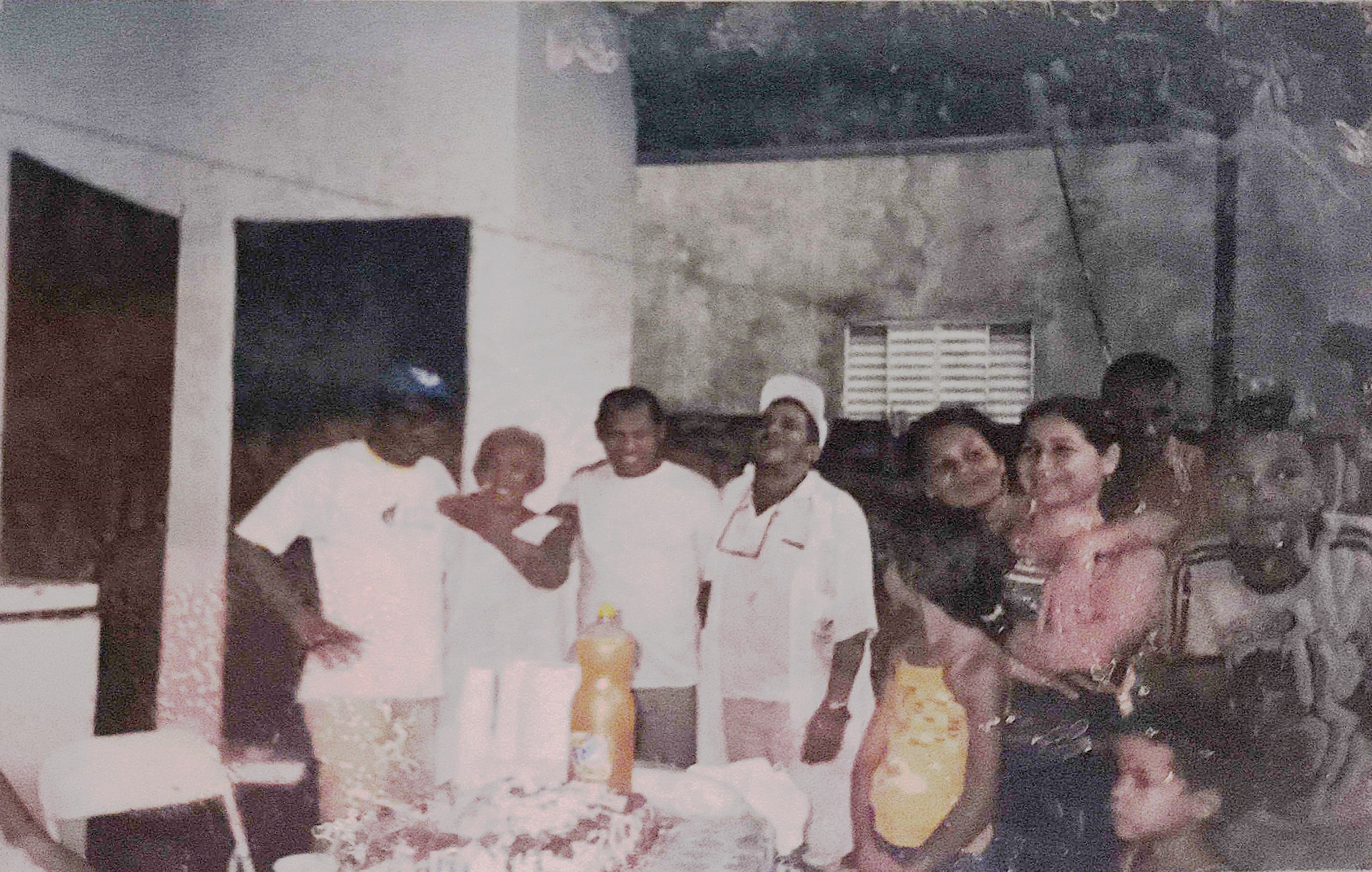 Registro de uma das festas realizadas na Vila Esperança. No centro da imagem estão Dona Martinha e seu filho Zumbi, abraçados diante de uma mesa com comidas e bebidas, evidenciando tanto o laço familiar quanto a força de sua atuação comunitária. Esses encontros eram momentos importantes de convivência, celebração e fortalecimento dos vínculos locais.