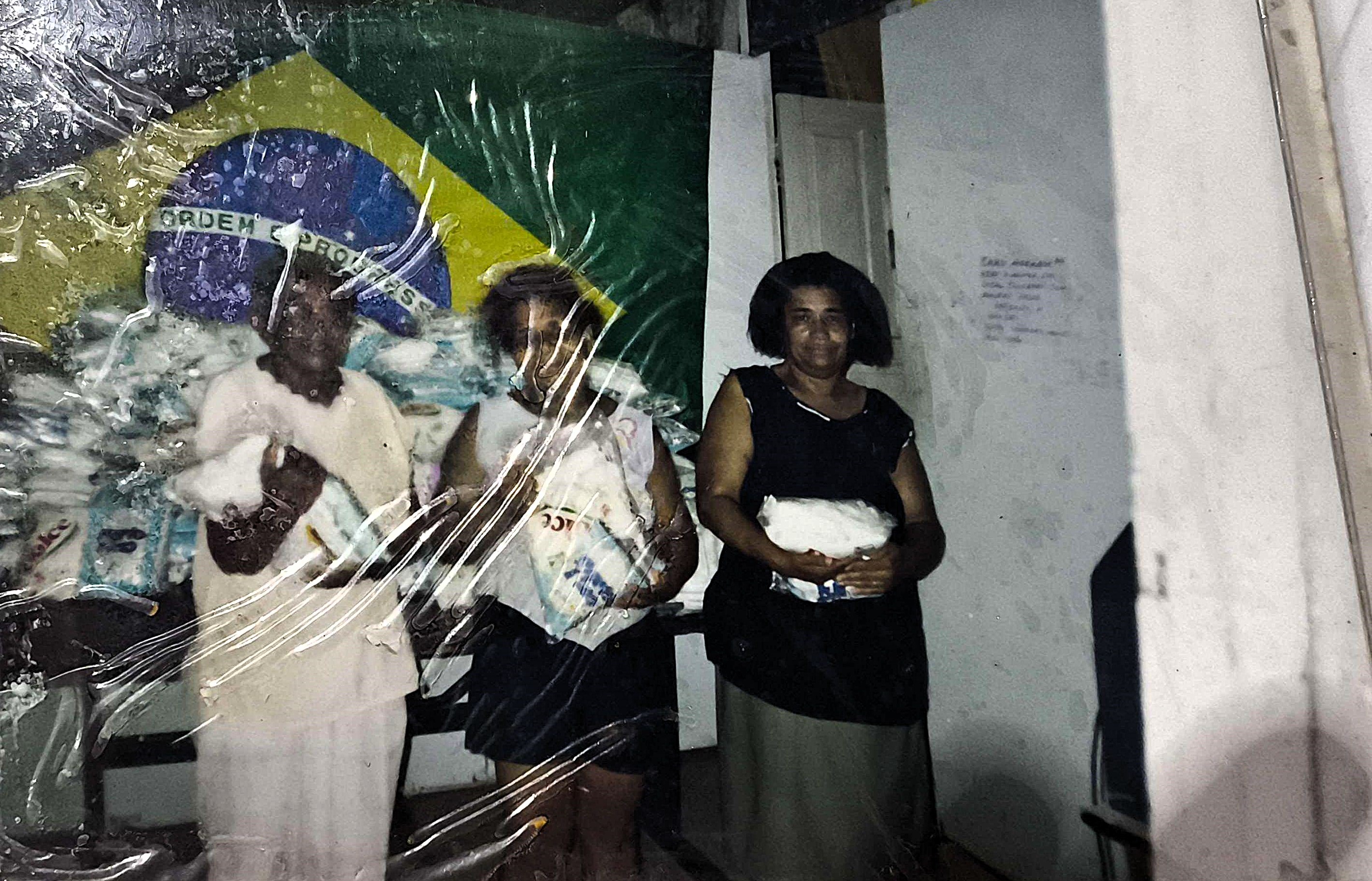 Na sede da Associação dos moradores da Ilha Bela, na Vila Esperança, Dona Martinha aparece ao lado de outras voluntárias engajadas na arrecadação de alimentos para atender famílias da região. A fotografia demonstra a força das ações solidárias promovidas pela ONG e o protagonismo dessas mulheres na criação de projetos que buscavam melhorar continuamente as condições de vida na Vila Esperança.