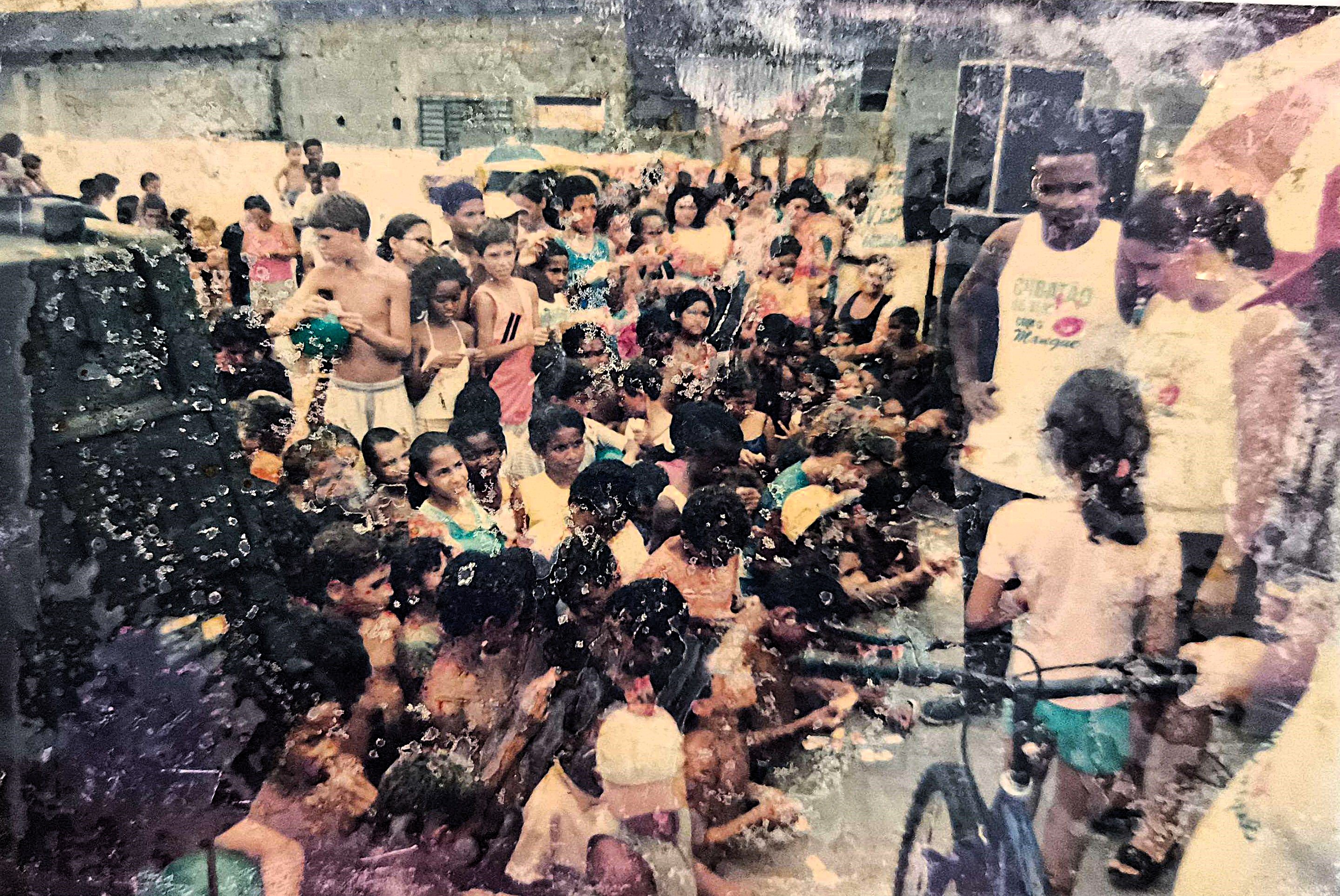 Fotografia de uma festa infantil promovida pela Associação de Melhoramentos da Ilha Bela. Zumbi aparece organizando o grande número de crianças da região, refletindo a vitalidade da comunidade e o esforço contínuo para garantir momentos de alegria, convivência e cuidado às infâncias locais. O registro revela um dia festivo, mas também o compromisso com a melhoria das condições de vida das famílias.