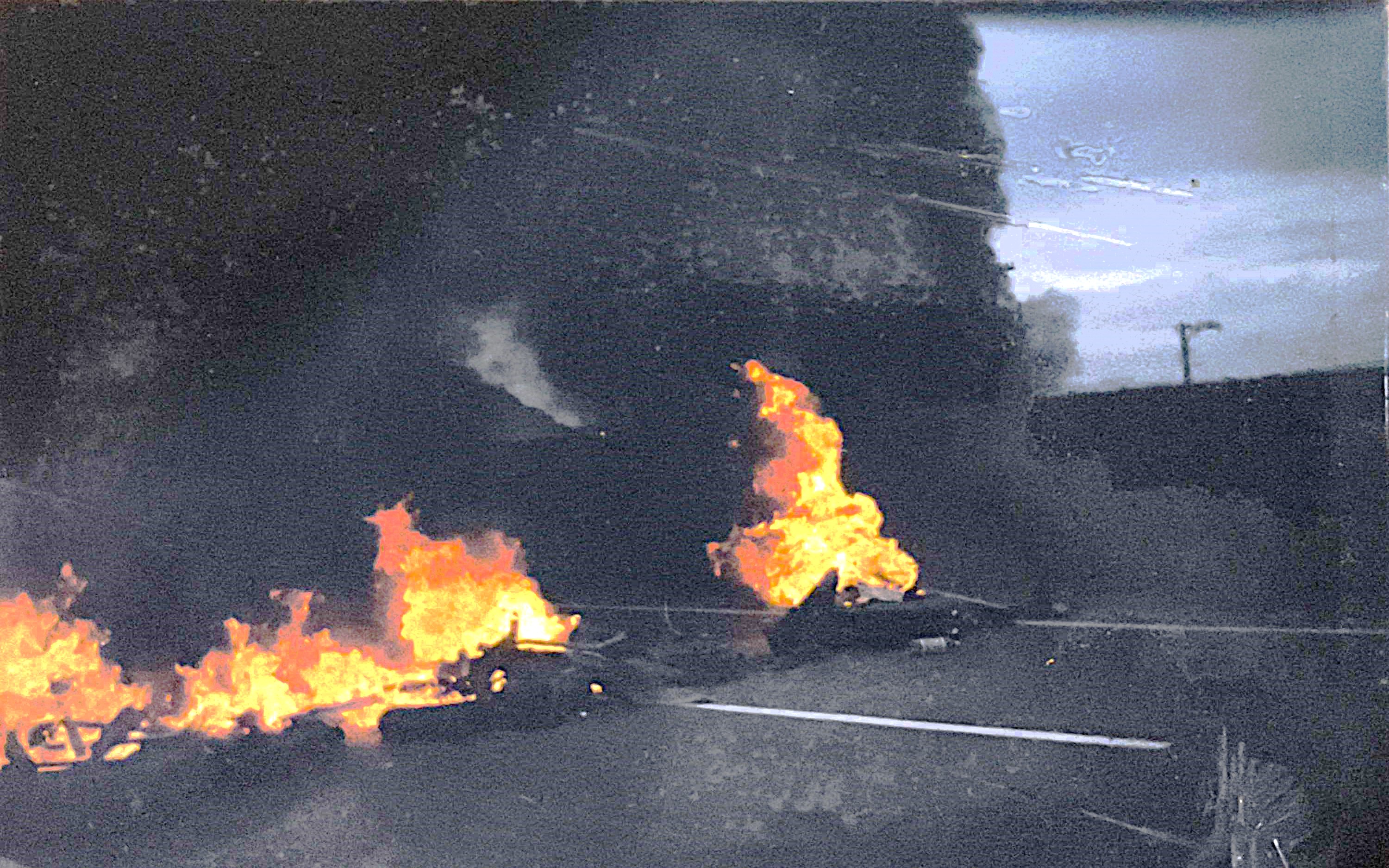 Nesta imagem, moradores da Vila Esperança bloqueiam a Rodovia Pedro Taques, atual Padre Manoel da Nóbrega via Anchieta, com pneus queimados para chamar atenção do poder público para a falta de rede elétrica na região. A ação gerou grande repercussão na imprensa e abriu caminho para negociações que resultaram, progressivamente, em melhorias para o bairro. A fotografia captura a intensidade de um momento decisivo da história comunitária.
