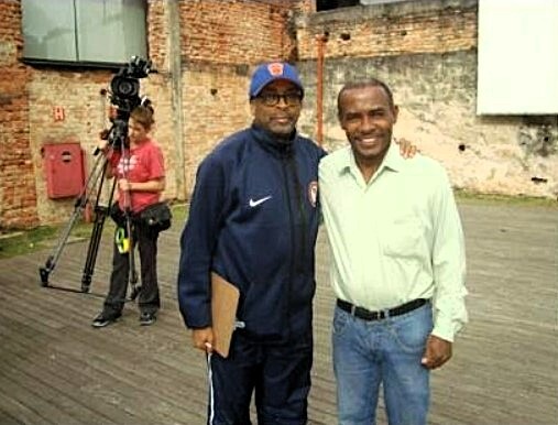 Zumbi e Spike Lee durante as filmagens do documentário “Go Brazil! Go!” O diretor buscava conhecer de perto iniciativas comunitárias e se interessou pelo trabalho no Mangue, na Vila Esperança, e pelos contrastes de Cubatão. No encontro, conversaram sobre desafios locais, potencialidades da cidade e como a vida nas comunidades ajuda a contar outras histórias do Brasil.