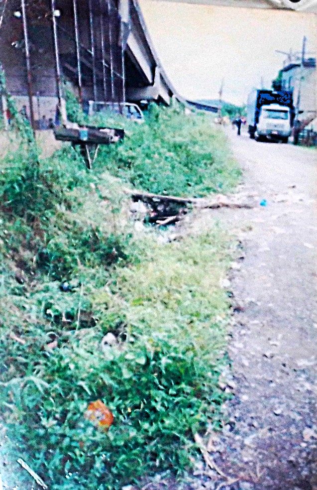 A fotografia mostra a Avenida Principal da Vila Esperança durante o início do processo de urbanização. Embora melhorias já estivessem em curso, o esgoto ainda corria a céu aberto. Ao fundo, observam-se as estacas da futura passarela da Rodovia dos Imigrantes. A imagem evidencia o ritmo lento da transformação urbana e a persistência das desigualdades no território.