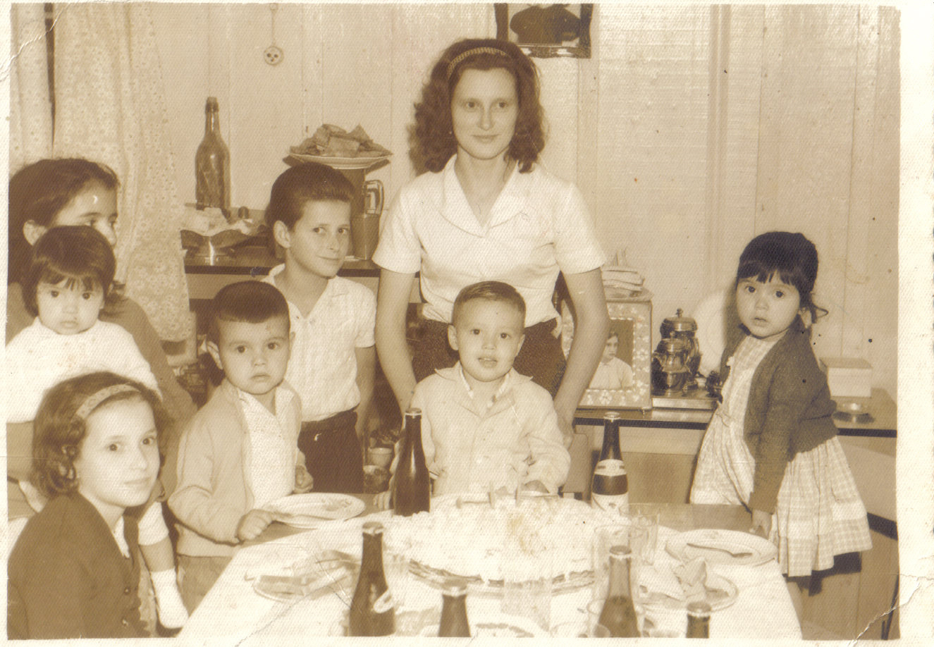 personagem: Minha mãe Maria, atrás de mim. Naor, Bernadeth, Paulinho, Bize e minha tia Zuleide.<br>historia: Esta é minha foto aos dois anos. Foi tirada em preto e branco e nela estão pessoas que já não estão entre nós, com o meu primo Naor e a sua mãe Zuleide. Naor foi um primo muito especial na minha vida. Passamos toda a nossa infância juntos. Ele falecem em 27 de agosto de 2006, dois dias depois do meu aniversário. Eu senti muito a sua morte, ele me deixou saudades.<br>