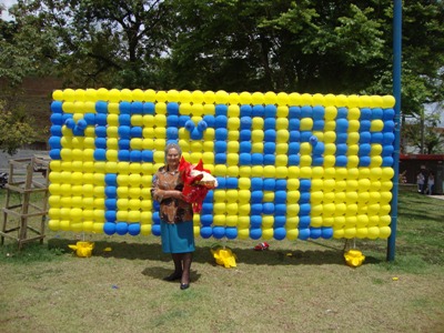 personagem: Dona Alaíde<br>historia: Dona Alaíde em frente ao mural com o nome do projeto Memória Local.<br>