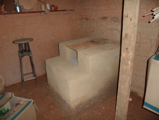 personagem: Aparece apenas o fogão no interior da casa de barro.<br>historia: A entrevistada construiu uma réplica na casa de barro batido para seus netos brincarem.<br>