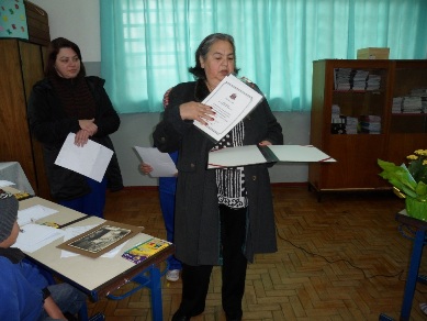 personagem: Dona Úrsula e professora Rosimara<br>historia: Dona Úrsula mostra para os alunos documentos pessoais que recebeu em homenagem ao seu trabalho como artesã.<br>