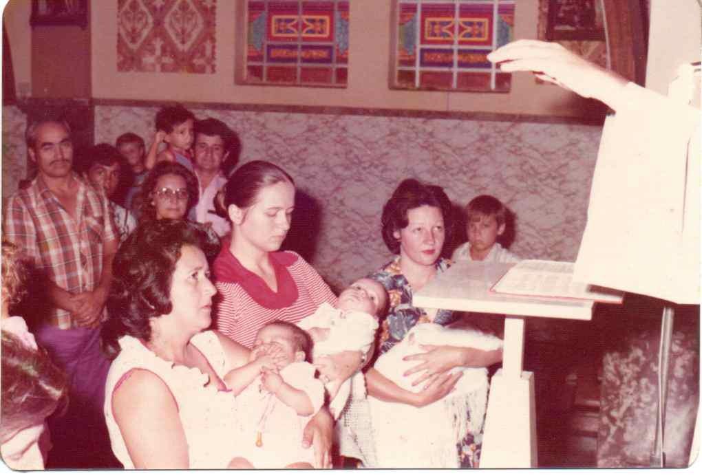 O batizado do seu filho aconteceu na Igreja São José, com as bênçãos do Padre Julinho. Adriano tinha 3 meses e seus padrinhos são Santa Rodrigues e Pedro Jacomini. As pessoas que estão com as crianças no colo, são mães que também estavam ali para o batizado de seus filhos.