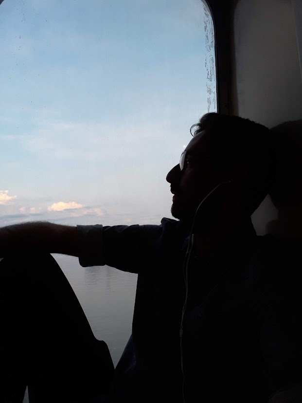 Carlos Eduardo durante uma viagem de barco entre a Argentina e o Uruguai. Nessa época, morava na Argentina e seguia viagem para visitar uma amiga no Uruguai. Ele conta que essa fotografia representa a importância que viajar tem em sua vida, sendo um momento de prazer, relaxamento, de conhecer outras culturas, lugares e aspectos da vida.