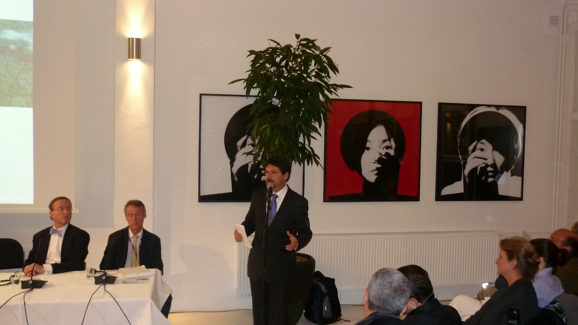 A fotografia registra o momento da fala de Binho durante a COP 15, realizada em Copenhague, em dezembro de 2009. Diante de representantes de governos, organizações e instituições de diferentes partes do mundo, ele participa das discussões voltadas à construção de soluções para os desafios impostos pelas mudanças climáticas. O registro destaca sua atuação em um espaço de diálogo internacional, levando às discussões globais as experiências e perspectivas relacionadas à Amazônia e ao desenvolvimento sustentável.