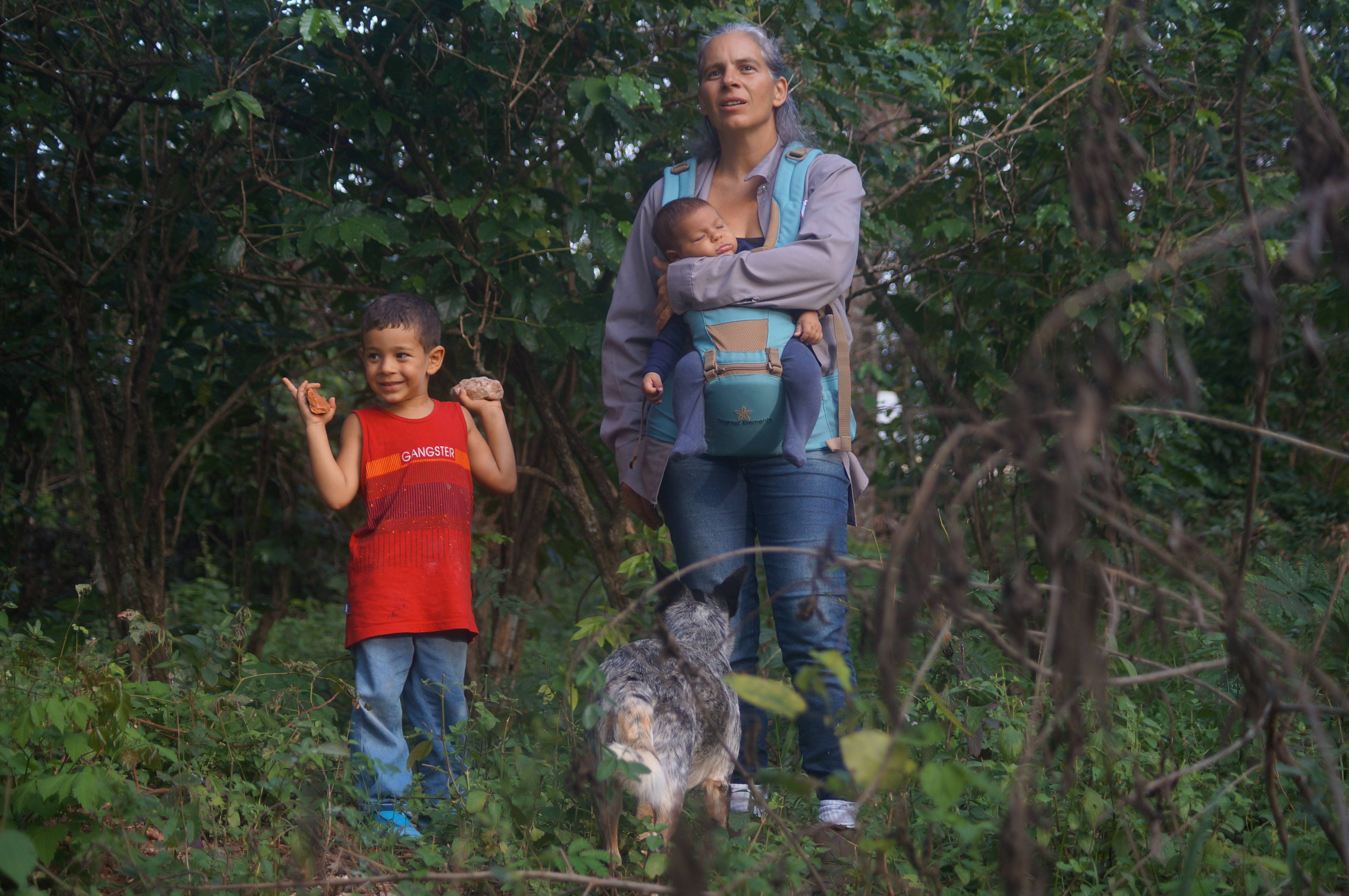 Malu, filha de João, caminha pela fazenda ao lado de seus filhos, Eduardo e Gustavo. A imagem revela um momento de conexão entre gerações, em meio à natureza.