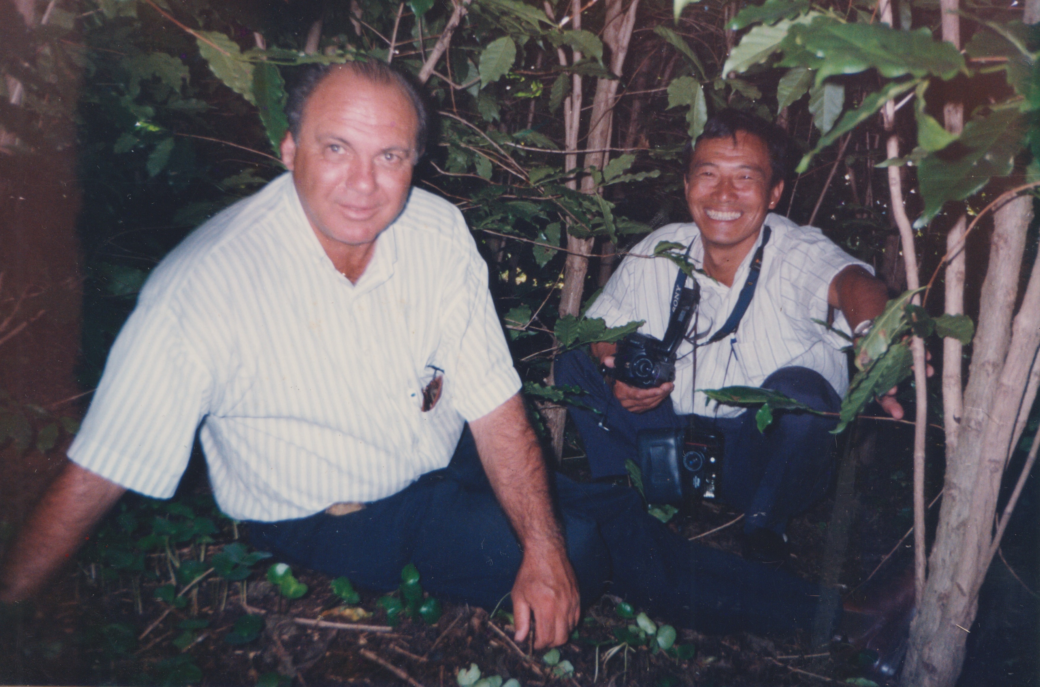 A imagem mostra João Pereira Lima Neto ao lado do senhor Tokoriki, exportador de café, durante a análise do solo em uma área de cultivo de café superadensado na Fazenda Santo Antônio da Água Limpa. A cena reflete a busca por conhecimento técnico e a adaptação da agricultura às novas demandas do setor.