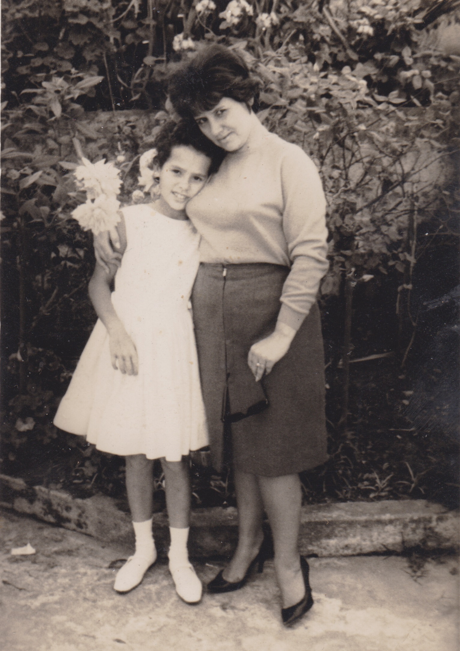 Silvana e sua mãe, Cida, posam para foto no jardim da casa de sua avó.