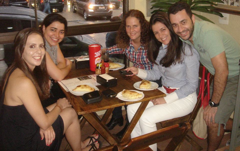 Guilherme com suas amigas em um bar na Vila Madalena, em São Paulo. Da esq. para dir., Maria Cristina, Roberta, Maíra, Vivi e ele. Ele conta que, antes da adolescência, não tinha muitas amizades e ao ingressar na Universidade de São Paulo, conheceu suas grandes amigas, mantendo contato até hoje. O grupo se conheceu em 1997 no curso de Economia da FEA-USP e se tornaram amigos para a vida inteira. Guilherme relembra que as amigas Daniela e Ana Paula, que não estão na fotografia, também são importantes pra ele.
