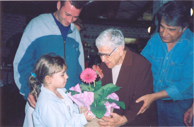 A tataraneta de Maria Aurora lhe entrega flores em seu 100º aniversário. Esq. Dir: Daniel, tataraneta, Aurora, Nelson