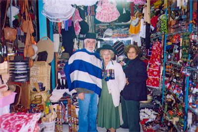 Rubem e Rosa posam com manto e sombreiro em uma loja de roupas típicas chilenas.