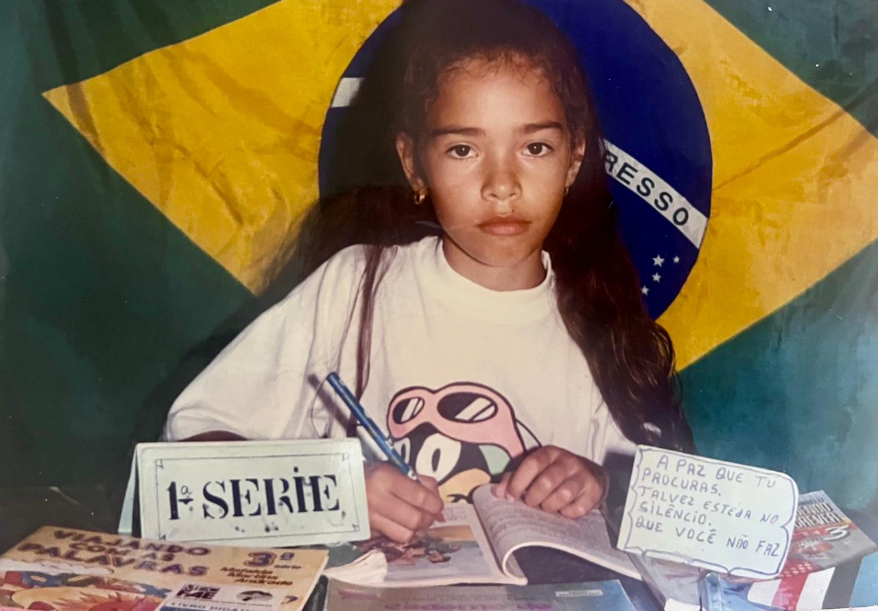 Foto escolar da primeira série, registrada durante o período em que Dayana viveu na cidade natal de sua mãe. A imagem lembra esse deslocamento, em um momento de formação em que a menina sentia muita saudade de São Paulo.