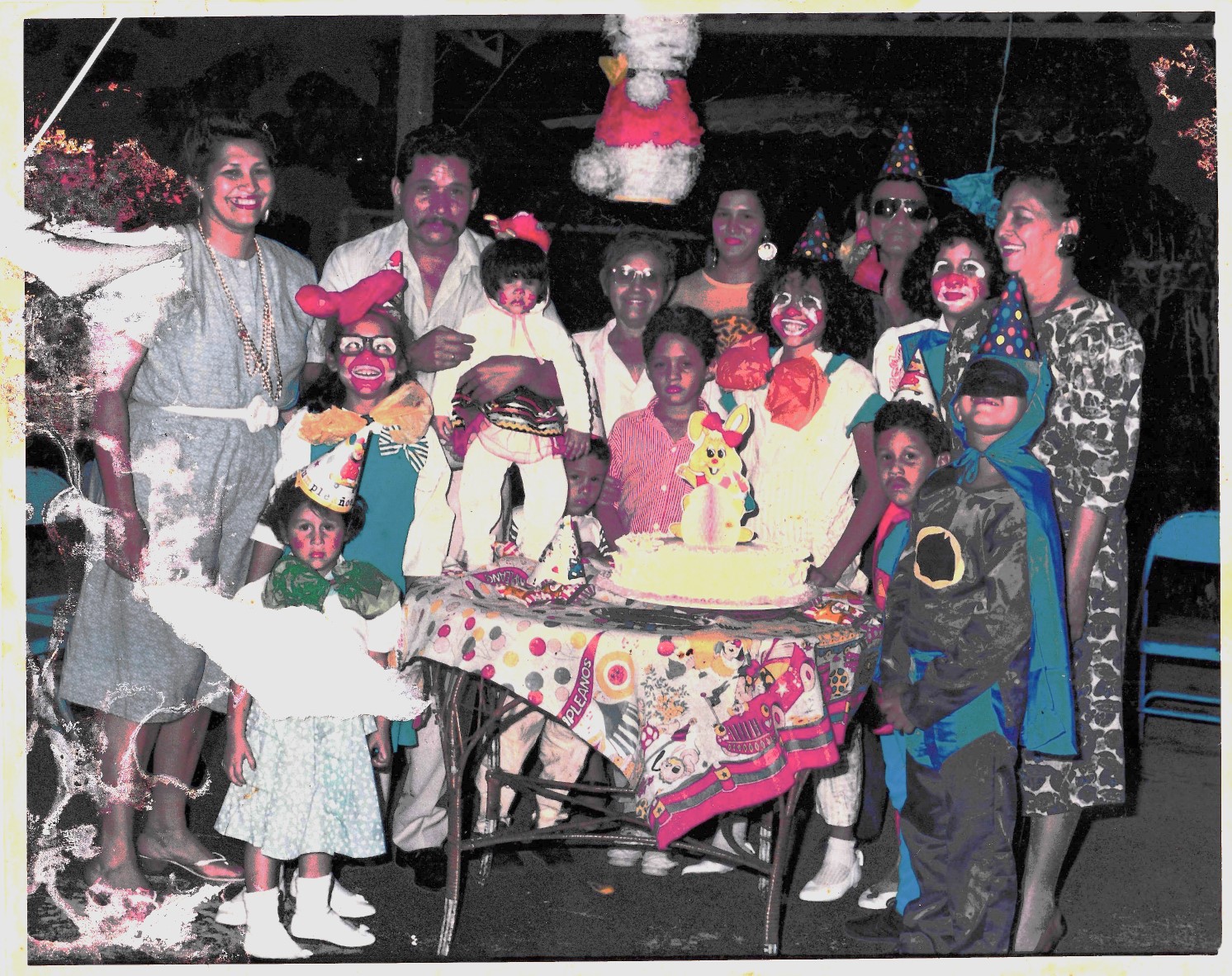 A fotografia registra o primeiro aniversário de Oriana, celebrado no quintal da casa onde vivia à beira do Lago de Maracaibo. Vestida com uma fantasia de coelho, que nem todas as irmãs e primos apreciaram , ela guarda dessa imagem um afeto especial: acha-se fofa e reafirma um carinho duradouro pelos coelhos. Estão presentes seus pais, Nieves Hernández e José Rafael; as irmãs María Fernanda, María Cristina e María Alejandra; os avós Blanca, Luisa e Alejo (Alejandro); a tia María Luisa (Maya); e os primos Bárbara, Félix, Leonel, Miguel e Juan (Chiche). A cena reúne gerações em torno de um rito íntimo, onde infância, fantasia e afeto se entrelaçam.