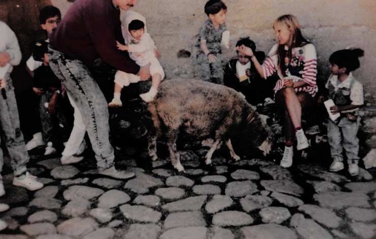 A fotografia mostra Oriana ao lado de seu pai, José Rafael, entre outros turistas, durante uma visita ao parque turístico La Venezuela de Antier, entre o final da década de 80 e início dos anos 90. Ela recorda que o pai a incentivava a interagir com as ovelhas, aproximando-se sem medo. A cena revela um gesto de cuidado e ensino, em que o contato com os animais fazia parte da experiência do passeio.