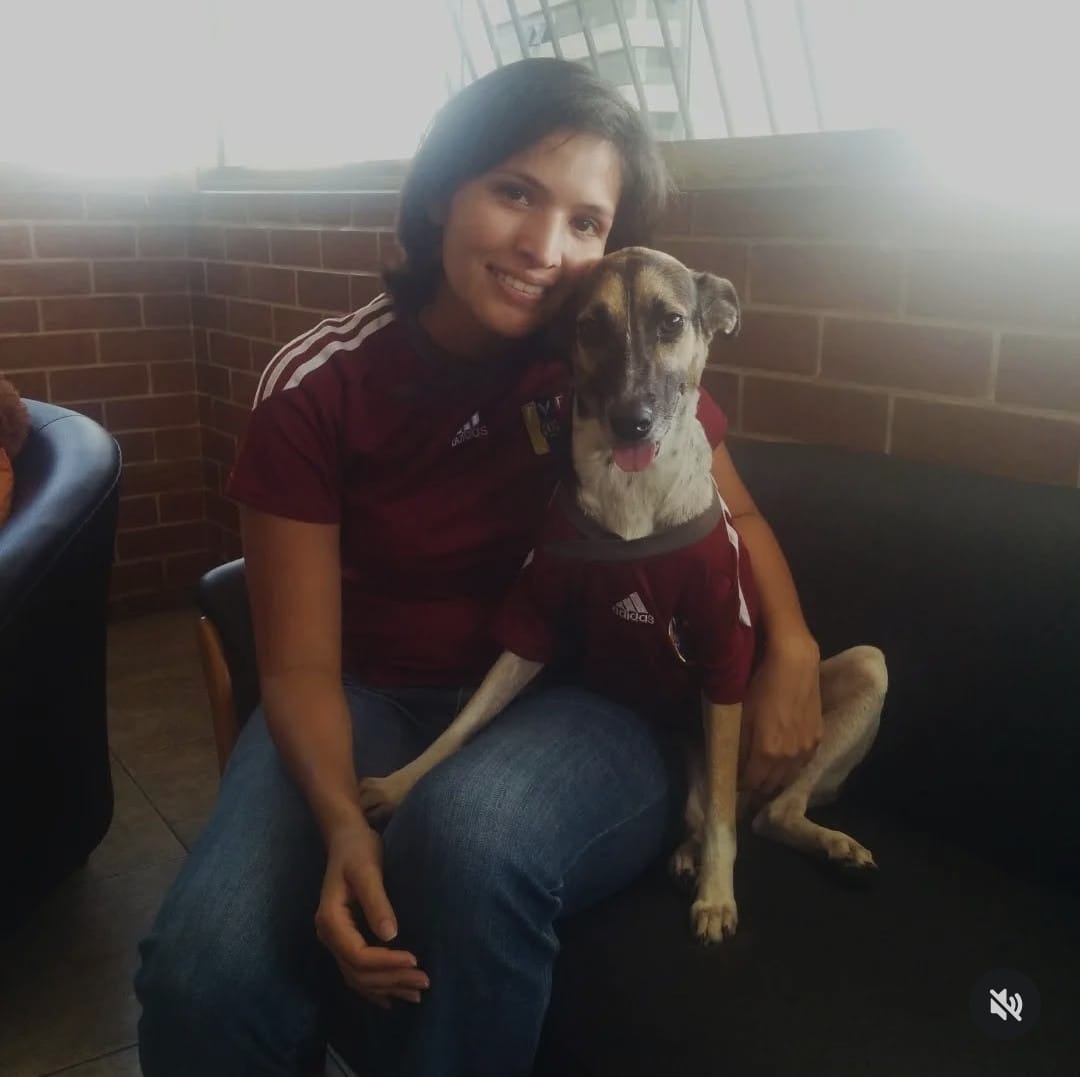 Era época de Copa do Mundo, e a cidade de Caracas pulsava com a energia dos jogos. Oriana, então moradora da capital venezuelana, costumava se reunir com amigos em bares para acompanhar cada partida. Foi nesse período que Marta, a cadelinha vira-lata, chegou de Zulia para se tornar parte inseparável da vida de Oriana. A fotografia guarda esse instante de chegada e adaptação: Marta, recém-trazida, ainda descobria os novos cheiros e ritmos da cidade, enquanto Oriana vivia a intensidade das celebrações esportivas.