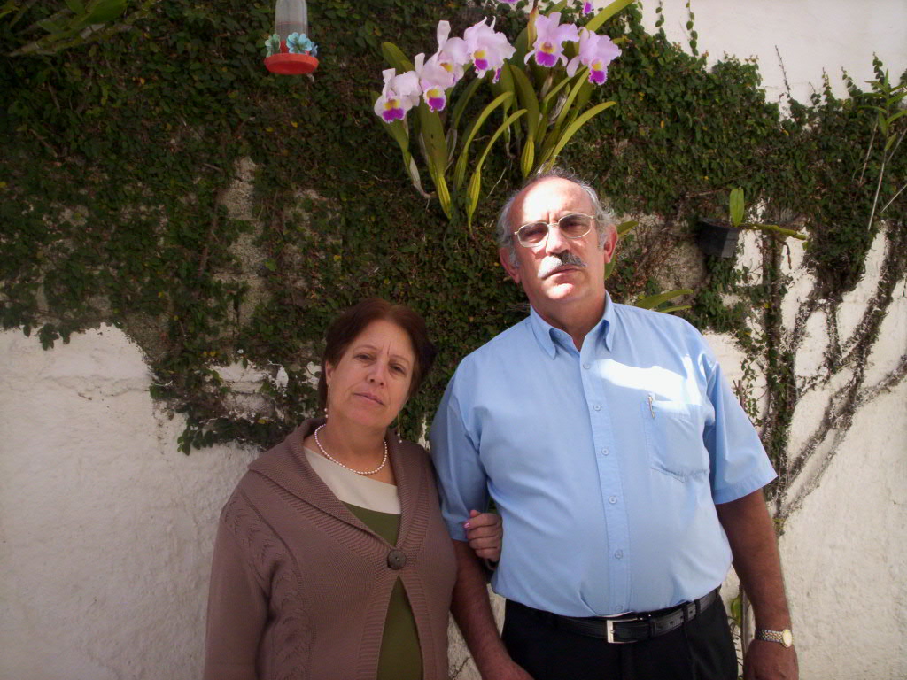 Eliane e Carlos, pais de Christiane, aparecem juntos no quintal da casa da família. A imagem registra um momento simples do cotidiano doméstico, destacando a presença do casal no espaço que serviu como núcleo de convivência e construção da vida familiar.