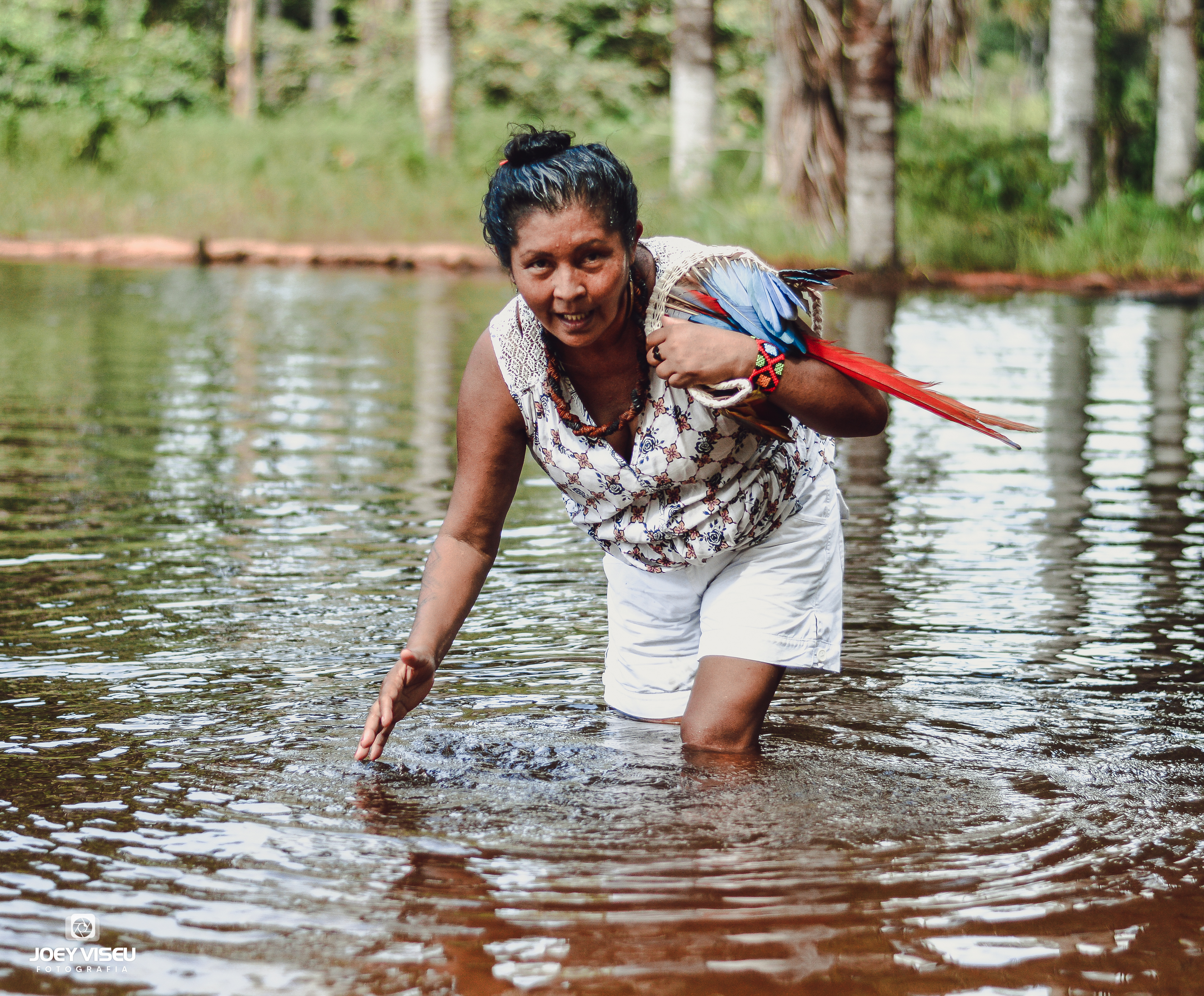 Essa foto foi tirada no igarapé. Luakam colocou a sua mão dentro d'água para pedir licença à mãe d'água para se banhar. Luakam está com um cocar, pois estava prestes a fazer uma oferenda ao Curupira, outro ser encantado. Esta oferenda consiste em oferecer o cocar em troca de bons fluídos, de paz, proteção, já que acreditam que o Curupira é o rei da mata e dos ancestrais, os grandes guerreiros que se foram.