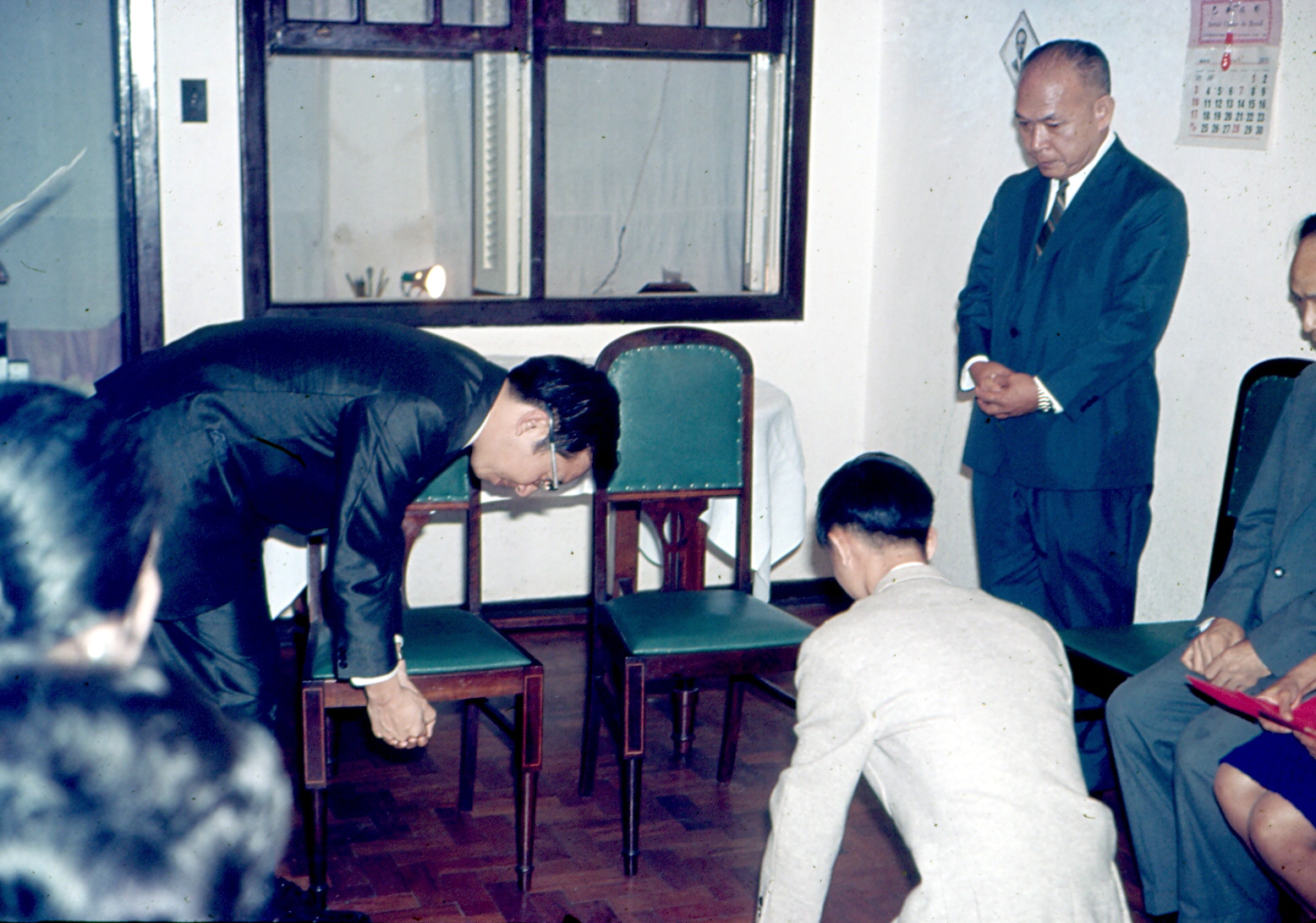 Cerimônia para ser aceito como discípulo do seu mestre, Sr. Sun, pintor de pintura chinesa clássica.
Cerimônia de reverência. Ele afirma que é uma cerimônia muito séria na China de antigamente. 
O mestre retribui a reverência em 90 graus, mas não ajoelha. Tai, de branco, está de joelhos.
O senhor em pé é como se fosse um padre em um casamento.
Foi tirada na casa de Tai, com vários amigos que participaram como testemunhas.
Tai foi discípulo de 1969 a 1977, quando se mudou para Goiânia (GO).