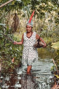 Luakam estava pescando o almoço de sua família. Ela estava balançando o pé para os peixes nadarem para o outro lado, onde estava uma rede. Luakam estava carregando uma croatá, em português significa bacia, para colocar os peixes.