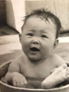 Nesta foto a Rosely está no quintal da sua casa. Seus pais tinham o costume de colocar ela e seus irmãos dentro do balde para refrescar, no verão, por conta da alta temperatura.