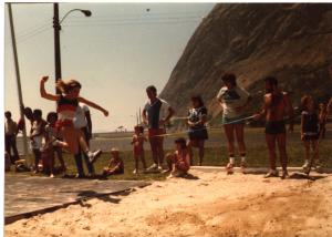 Maria Lúcia prestes a realizar o pulo que lhe daria a medalha de ouro da modalidade de salto em altura nas olimpíadas realizadas no Forte de São João, na Urca. Sua filha Renata está sentada ao fundo.