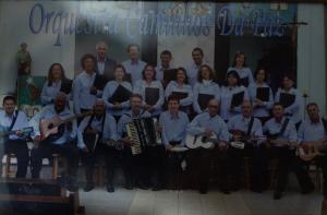Nesta foto, Seu Jorge está junto de sua esposa e de casais de amigos na Orquestra Caminho da Paz. Trata-se de uma orquestra sertaneja.