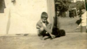 José Antonio e seu cachorro, Pelé, em frente à casa de sua tia Lina, uma segunda mãe. No lado direito da fotografia, Corina, sua mãe.